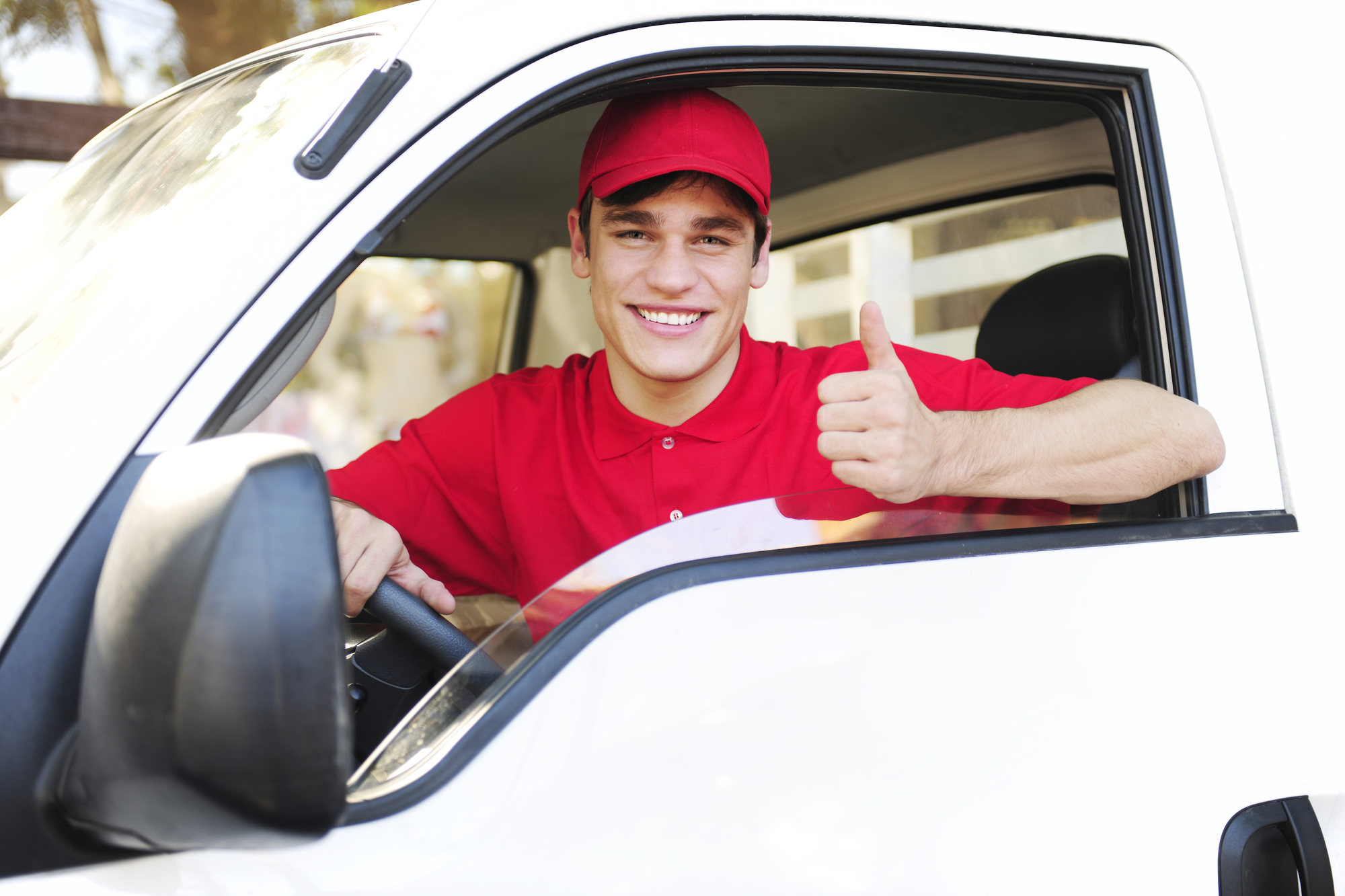 male postal delivery courier in a van showing thumb up hand sign